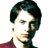 Pixelated static image of a person's head and shoulders with dark hair, light skin tone, and partial red clothing visible against white background.