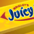 Yellow candy package with blue text 'Juicy Fruit' and red accents, showing partial views of the brand name across four quadrants.