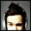 A static close-up of a person's upper face and head wearing large silver headphones against a plain gray background.