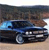 Pixelated image of a dark blue sedan with visible headlights and wheels on a light brown surface under a dark background.