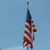 A pixelated flag with red and white stripes and a blue field, mounted on a pole against a light blue background.