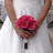 A pixelated image shows a person holding a large red flower bouquet with both hands raised above the head, wearing a white shirt with a black rectangular detail on the chest.