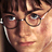 Pixelated close-up of a person with brown hair, round glasses, and light skin tone wearing a dark shirt.