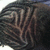 A close-up of a person's head with dark braided hair featuring light brown highlights, viewed from the side against a bright background.