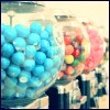 A static image shows a person holding two large bags of colorful candies, one blue and one multicolored, with a blurred background.