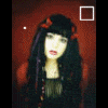A static image of a person with long dark hair and red bows, wearing a dark top against a reddish-brown background.