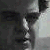 Pixelated grayscale image of a person in profile view wearing a light-colored shirt against a dark background.