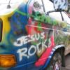 A blurry static image of a vehicle with colorful graffiti reading "JESUS ROCKS" in white letters on a blue background, with visible orange and red accents.