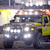 Pixelated image of a dark-colored vehicle with yellow accents, headlights on, and a blurred background suggesting motion or low resolution.