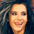 Pixelated close-up of a smiling person with light skin and dark eyes against a dark blue background, hair visible on left side.