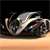 A pixelated car with a silver roof and dark body rests on a light brown surface against a black background.