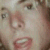 Pixelated close-up of a person's face showing eyes, nose, mouth, and partial cheek with muted skin tones and brown hair elements.