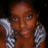 A pixelated close-up of a person with brown skin tone wearing silver chain-link jewelry against a dark background.