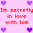 Pixelated pink background with red text repeating 'Im secretly in love with him' and purple heart symbols at corners and center.