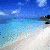 A four- beach scene with palm trees, blue sky, and water transitioning from day to sunset