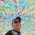 Pixelated image of a person with dark hair and sunglasses against a multicolored pixel grid background.