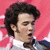 A person with dark curly hair and a white-collared shirt appears in four against a red background, showing subtle facial expression changes