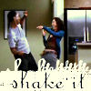 Three people in a kitchen pose with arms raised, one in a white shirt, another in blue, and a third in brown, with 'shake it' text below.