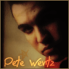 A close-up portrait of a person with dark hair and a red garment, overlaid with orange handwritten text reading "Pete Wentz".
