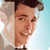 Pixelated close-up of a person with short dark hair, light skin, and a neutral expression, wearing a light-colored shirt against a gradient background.