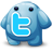Pixelated blue creature with rounded body, two small dark eyes, and a large light blue 'T' symbol on its chest against a gray background.