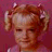 A pixelated image of a young girl with blonde pigtails and pink hair accessories against a solid red background, paired with black text on the right side reading "I'm not a snitcher. I just tell it like it is" in a blocky font.