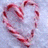 A static image with a green background, featuring a heart-shaped arrangement of red and white striped candy canes on the left side.