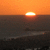 Sunset over water with orange sky and dark sea, showing three of the sun's position changing across the horizon
