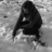 A grayscale pixelated image of a dark, indistinct figure with long hair against a light gray background.