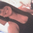 Pixelated image of a person with dark hair wearing black clothing, making a hand gesture against a light background.