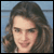 Static 50x50 pixel icon showing a person with long dark brown hair against a light blue background, rendered in low-resolution pixel art style.