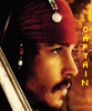 A close-up profile of a man with dark hair and mustache wearing a red turban, white earring, and sword; vertical yellow text reads CAPTAIN on left side.