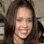 A static pixelated image shows a person with long dark hair smiling, wearing a dark top against a blurred background.