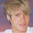 Pixelated close-up of a person's face with light brown hair and neutral expression against blurred background