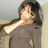 Pixelated image of a person with dark hair wearing a brown top, extending an arm forward with a light-colored sleeve visible.
