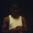 Pixelated image of a person wearing a light-colored tank top against dark background with brown shoulder accents.