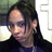 Static pixelated image of a person with dark hair and light skin wearing a dark top, set against a blurred background.