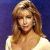 Pixelated image of a person with long light brown hair wearing a white top against a dark blue background.