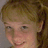 Pixelated close-up of a person with light brown hair tied back, showing eyes, nose, mouth, and part of the ear against a neutral background.