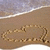 Pixelated beach scene with light brown sand, white wave crest, and muted blue-gray sky.