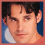 A pixelated portrait of a person with dark hair against a blue background, showing two expressions: neutral and smiling.