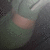 A pixelated close-up of a light green object with a pink band against dark gray background, showing subtle brightness variation