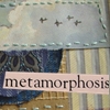 A static icon with a stitched border, featuring a cloudy sky with four small birds, a blue patterned section, and a beige striped section, with the word 'metamorphosis' in dark text on a light pink rectangle.