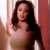 Static 50x50 pixel icon showing a woman with long dark hair in a light-colored sleeveless top against a blurred background with vertical elements.