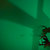 Pixelated green-toned image with indistinct shapes and minimal visible detail, featuring a small dark patterned section in the lower right corner.