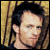 Pixelated static image of a person with dark hair against a striped background, showing partial facial features and neck.