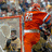 Pixelated image with blue background, white text, and a small inset photo of a person in orange clothing.