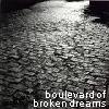A grainy black-and-white image with a bright light source at the top, featuring pixelated text at the bottom reading 'boulevard of broken dreams'.