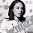 Pixelated grayscale image of a person with shoulder-length dark hair wearing a white top, set against a light background with scattered dark spots.
