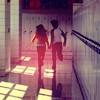 Two figures run hand-in-hand down a school hallway with lockers and a tiled floor, bathed in warm pink and yellow light.